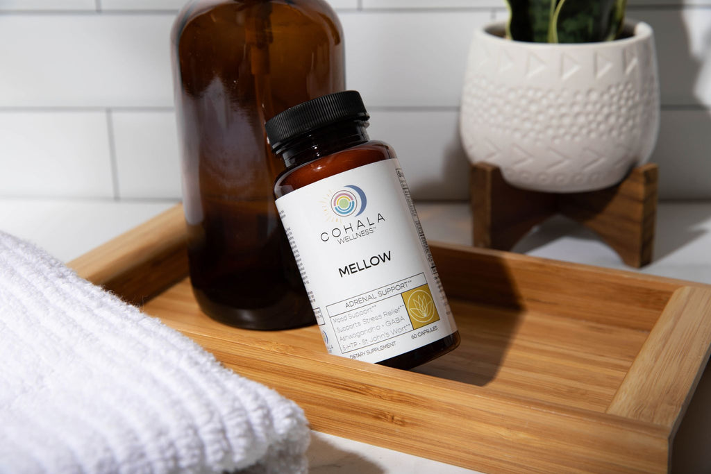 COHALA Wellness Mellow supplement bottle on a wooden bathroom tray with a towel and potted plant