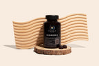 COHALA Wellness Mushroom X supplement bottle on a wood slice in front of a wavy wooden backdrop