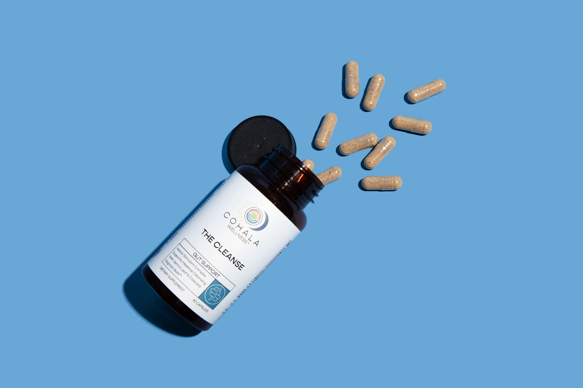 COHALA Wellness The Cleanse supplement bottle with capsules spilling out on a blue background